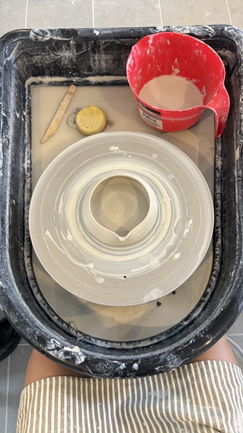 A freshly thrown clay pot on a pottery wheel